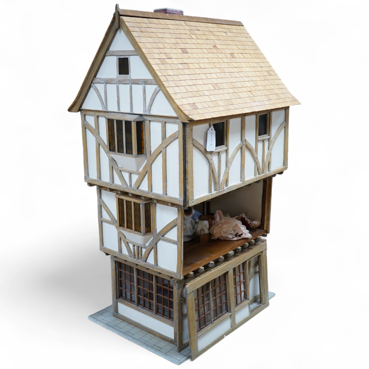 A modern doll’s house in the form of an oak framed Tudor house on three floors, with a shop on the ground floor, removable front panels on each floor and one side of the roof, with internal detailing and a good selection